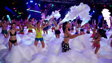 energetic young people dancing and enjoying foam party atmosphere, surrounded by vibrant soap bubbles and pulsing colorful nightclub lighting