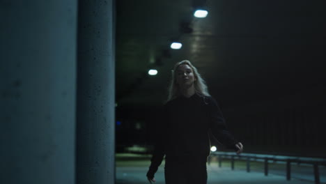 Night-city-woman-walking-confidently-with-blonde-hair-in-underground-tunnel.