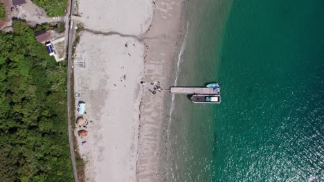 Vertical-Drone-fly-Aerial-Japanese-Coastline,-White-Sand-Beach-Sail-Boat-Japan-natural-environment-turquoise-calm-water,-slow-motion-establishing-shot-at-Wakayama-Island