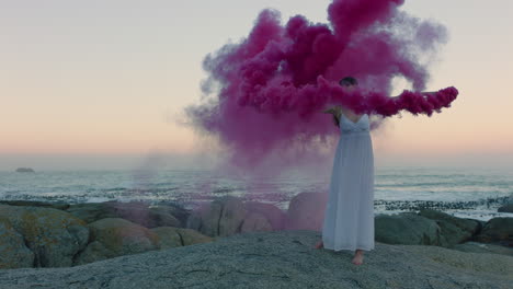 Mujer-Sosteniendo-Una-Bomba-De-Humo-Rosa-Bailando-En-La-Playa-Temprano-En-La-Mañana-Celebrando-La-Libertad-Creativa