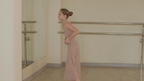 a group of young ballet students in black dancewear practicing positions in a spacious ballet studio with wooden flooring and wall-mounted barres. focused expressions and synchronized movements.