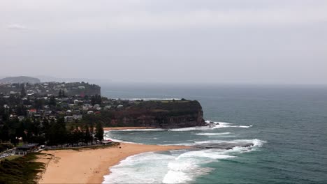 overcast day at a coastal cliffside and beach community, waves washing ashore on a sandy beach