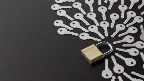 padlock and several keys on wooden table