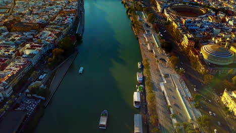 aerial shot looking down at the guadalquivir river, seville spain and tilting up to the sunset on the countryside skyline 4k 23fps