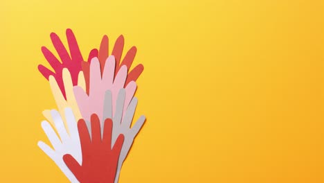 cerca de las manos juntas hechas de papel de colores sobre fondo amarillo con espacio para copiar
