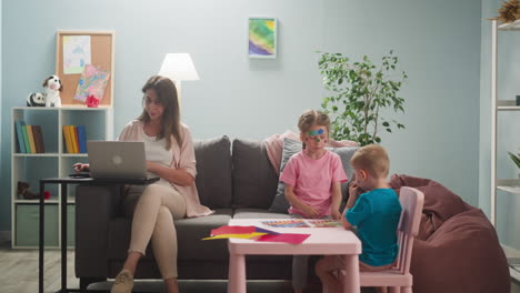 woman works on laptop neglecting playful children in room