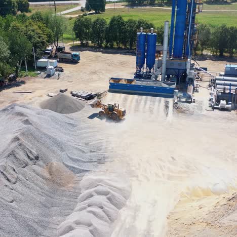 modern asphalt plant among piles of rubble. bulldozer working on the territory of asphalt factory. aerial view.