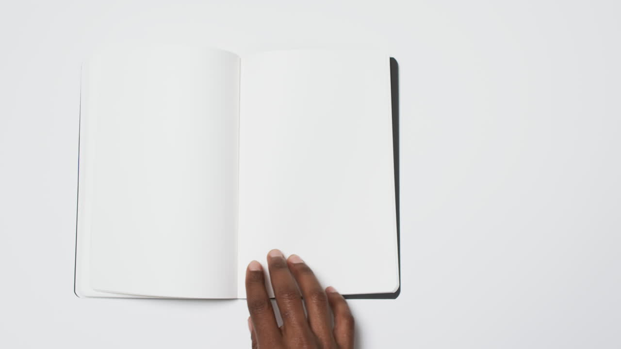Video of hand of african american man holding book with blank page, copy space on white background