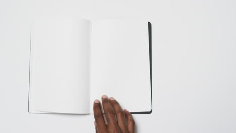 video de la mano de un hombre afroamericano sosteniendo un libro con una página en blanco, espacio de copia en fondo blanco