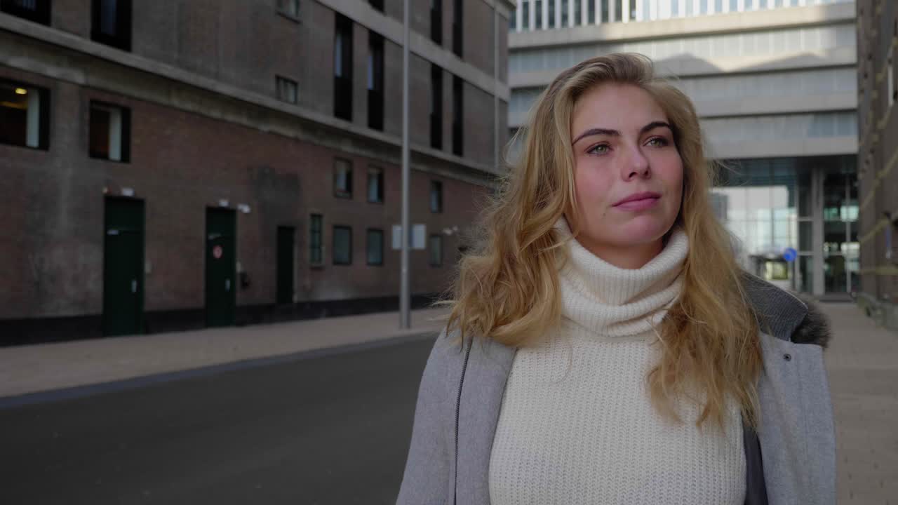Ung voksen blond kvinde går selvsikkert ned ad en byvej
