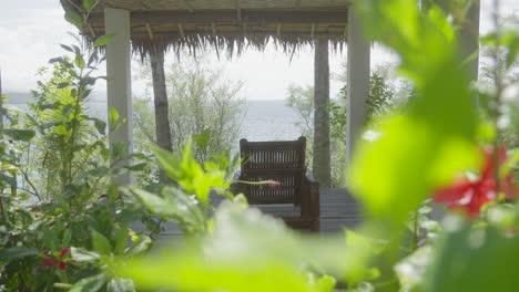 Wooden-open-hut-relax-area-with-sunbed-wide-shot-with-flowers-in-the-foreground