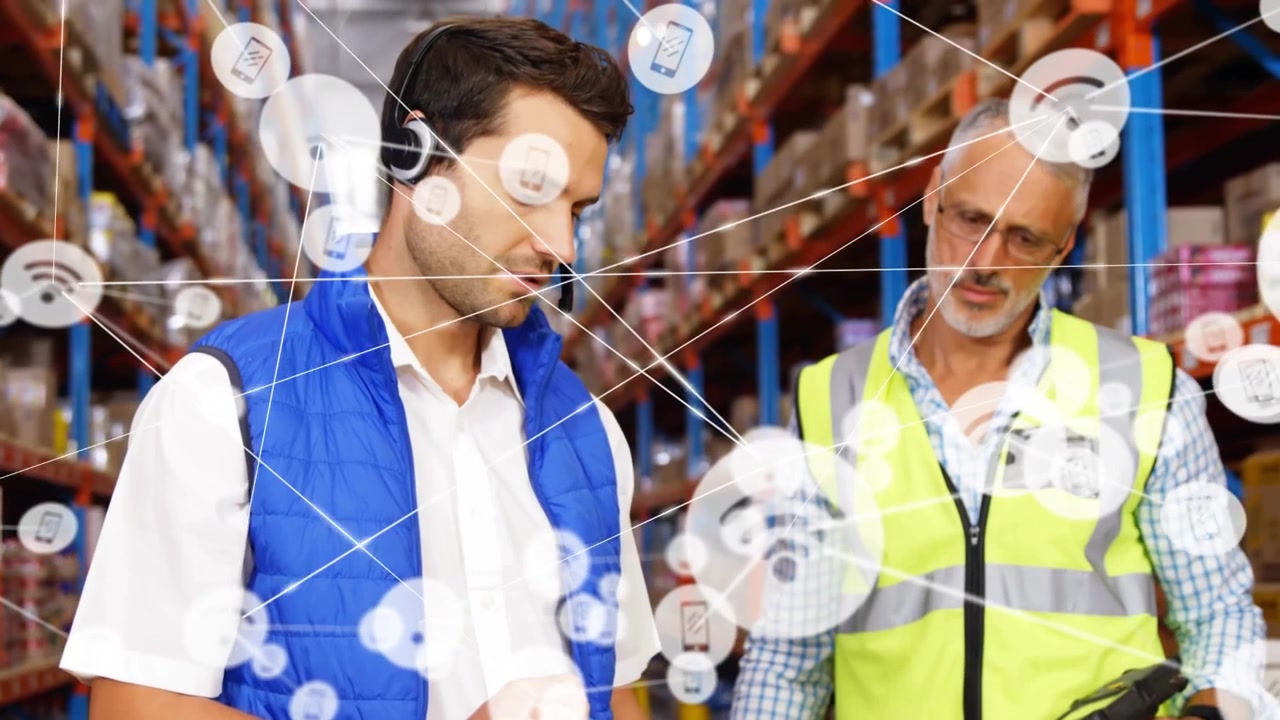 Personale della logistica che risponde all'auricolare, tocca un blocco note, scansiona, creando una rete IoT per l'inventario