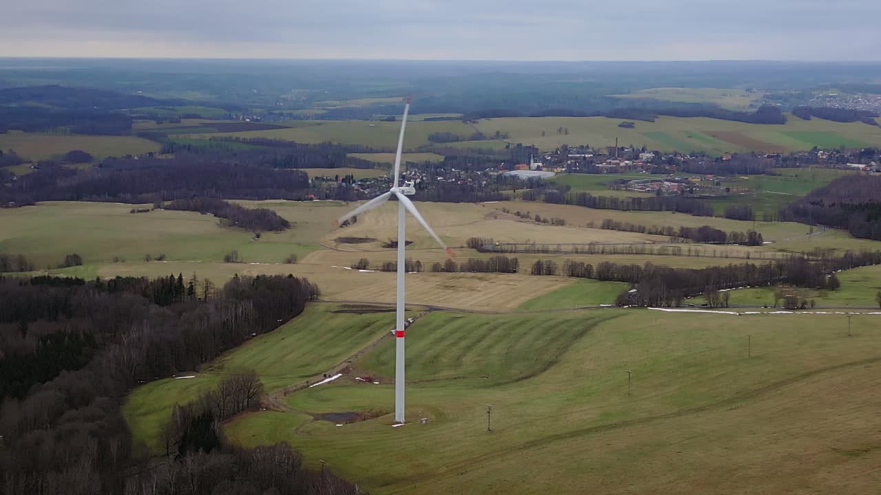 Ripresa aerea di una turbina eolica nel mezzo di un paesaggio montuoso.