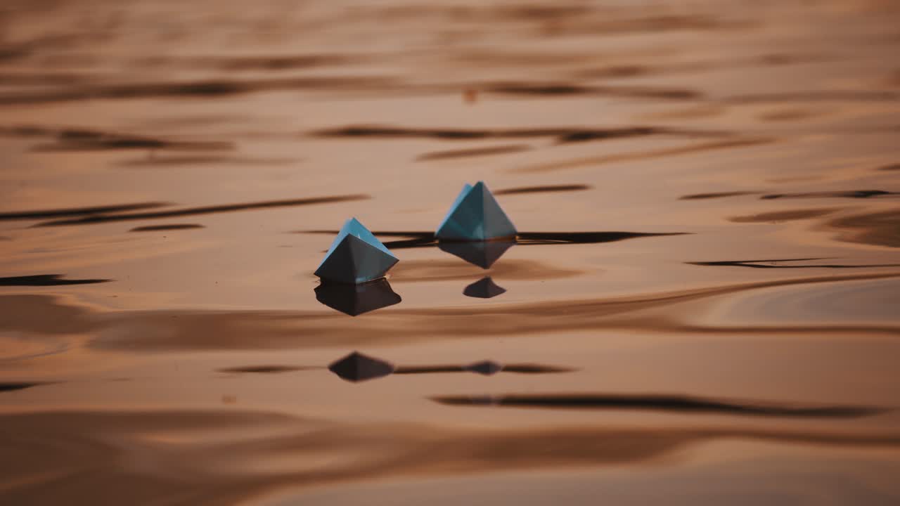 Evening water background and two paper boats swimming. Homemade origami ships floating on beautiful water surface.