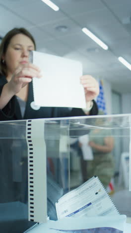 Diverse-voters,-American-people-vote-for-future-president-in-voting-booths-at-polling-station.-Caucasian-woman-puts-ballot-in-box.-National-Election-Day-in-the-United-States-of-America.-Slow-motion.