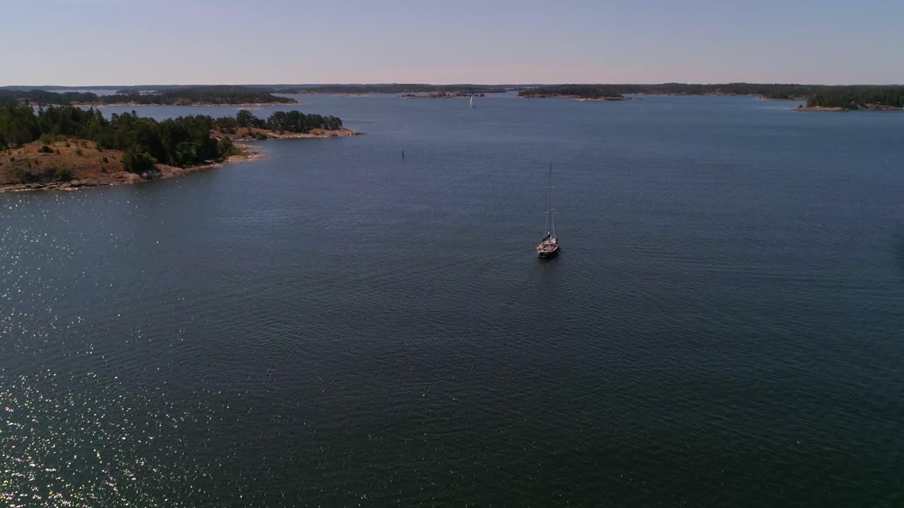 C4K aerial view of a Sailboat sailing between islands,  in the finnish archipelago, on a sunny summer day, in Kasnas, Saaristomeri national park, Varsinais-suomi, Finland