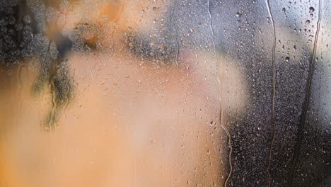 steamy shower glass wall with water drops against woman back