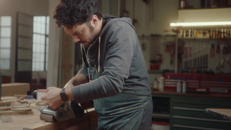 woodworker finishing chair leg with belt sander