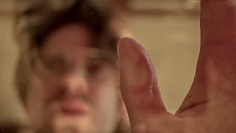person and hand behind blurred glass