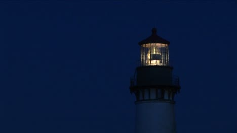 un primer plano de la baliza en la parte superior de la torre del faro por la noche