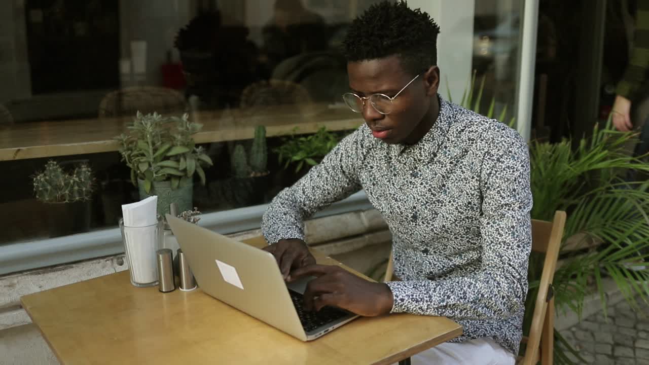 Young African American man using laptop in cafe