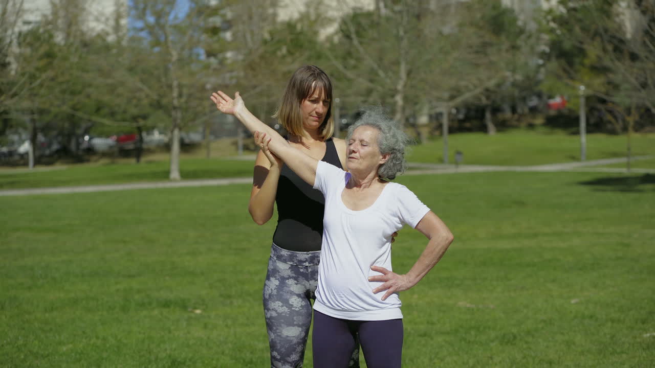 una mujer de último año sonriendo entrenando con el entrenador en el césped verde.