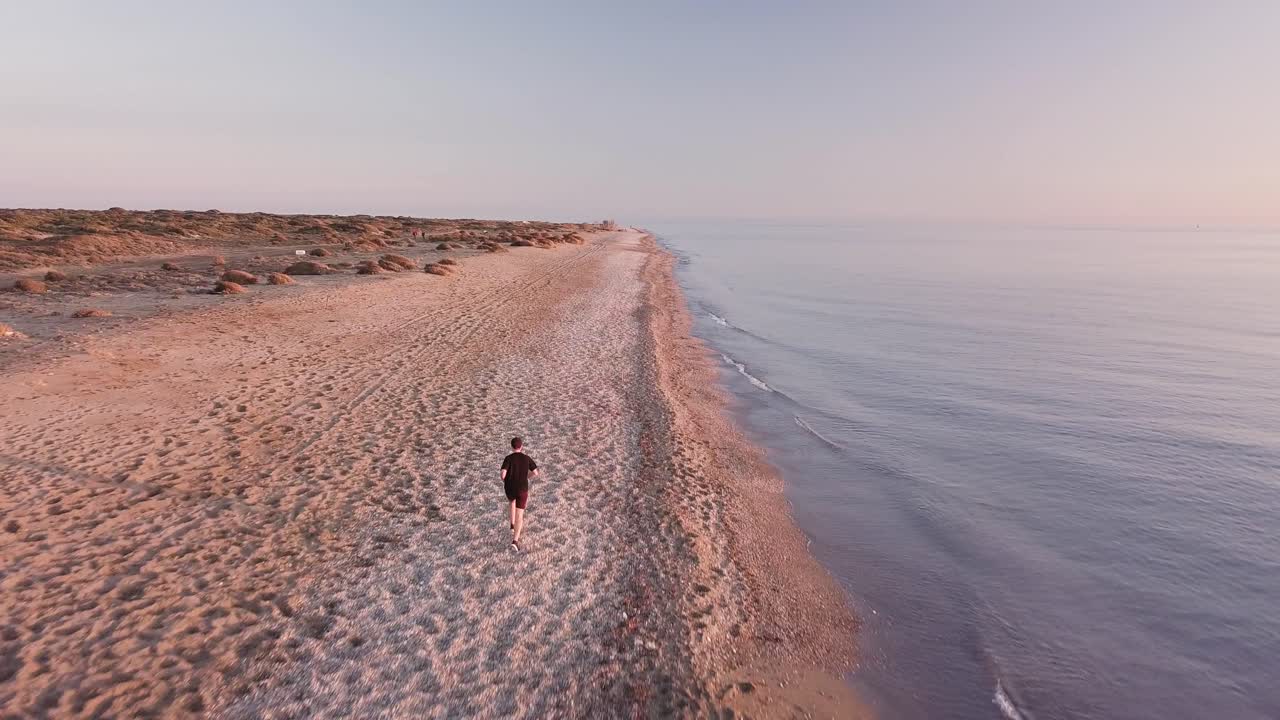 Young runner man training on beautiful sunset at beach