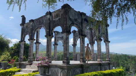 enchanting romance at taman ujung water palace: young girl in dress explores historic stone structure with pillars in east bali