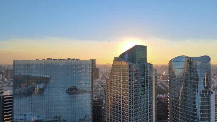 Vista aérea ascendente de edifícios altos com janelas de vidro refletindo os cais de Puerto Madero ao pôr do sol, Buenos Aires