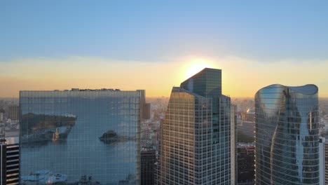 aerial rising on high-rise window glass buildings reflecting puerto madero piers at sunset, buenos aires