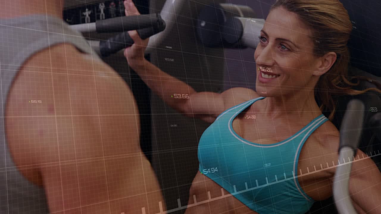 Woman placing hands on machine and pulling handles while man spotting, green graph tracking fitness