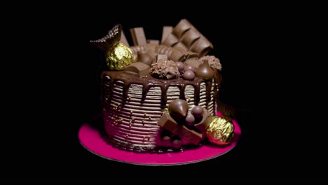 chocolate cake revealed from a silhouette in front of a dark background to fully lit with chocolates laid on top and sides of this 2 tier cake