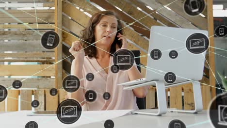 animation of network of digital icons over caucasian woman talking on smartphone at office