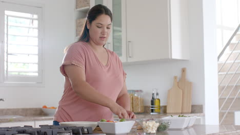 Feliz-Mujer-Birracial-De-Talla-Grande-Cortando-Verduras,-Haciendo-Comida-En-La-Cocina,-Copiando-Espacio,-Cámara-Lenta