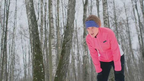 a young woman on a morning jog in the winter forest was tired and stopped to rest and ran on. he recovered his strength and overcame fatigue and continued to run. perseverance and overcoming weakness. striving forward. slow motion. healthy lifestyle