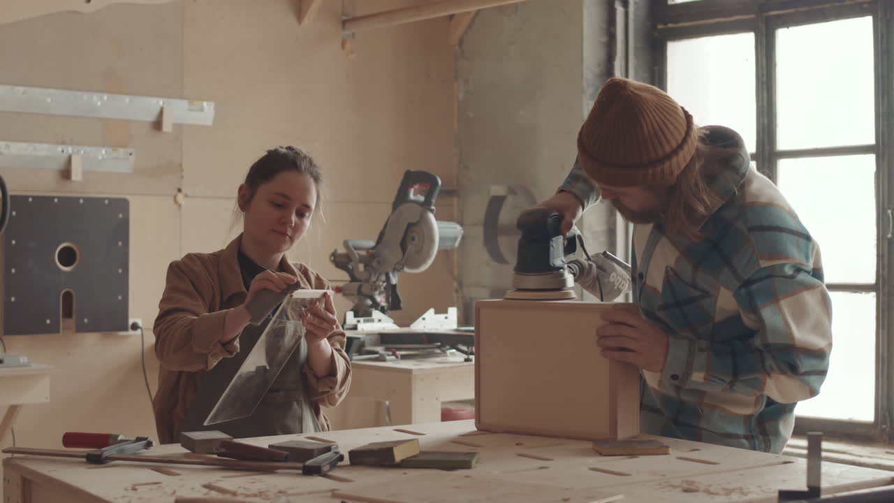 Two People Sanding Wooden Box in Joinery Workshop