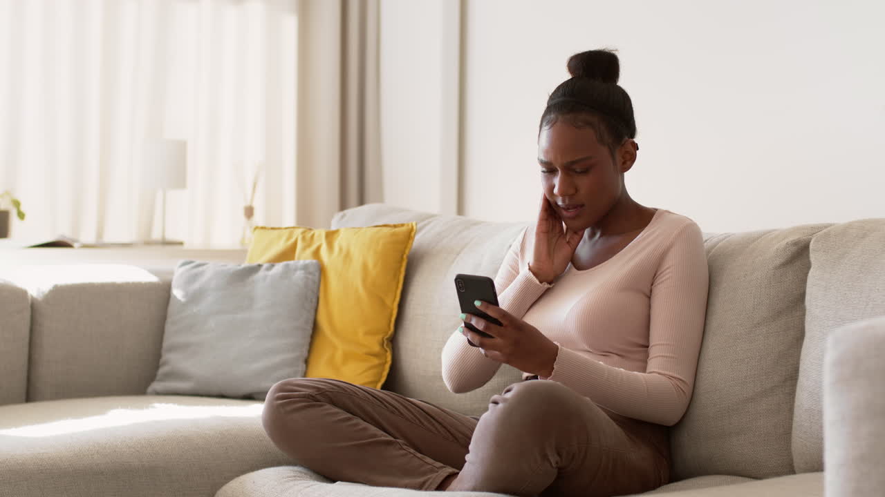 Mulher Lendo uma Mensagem de Texto em um Sofá