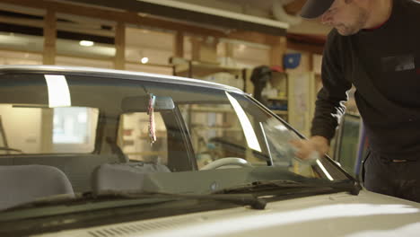 Auto-glass-technician-wipes-newly-replaced-car-windshield-after-installation