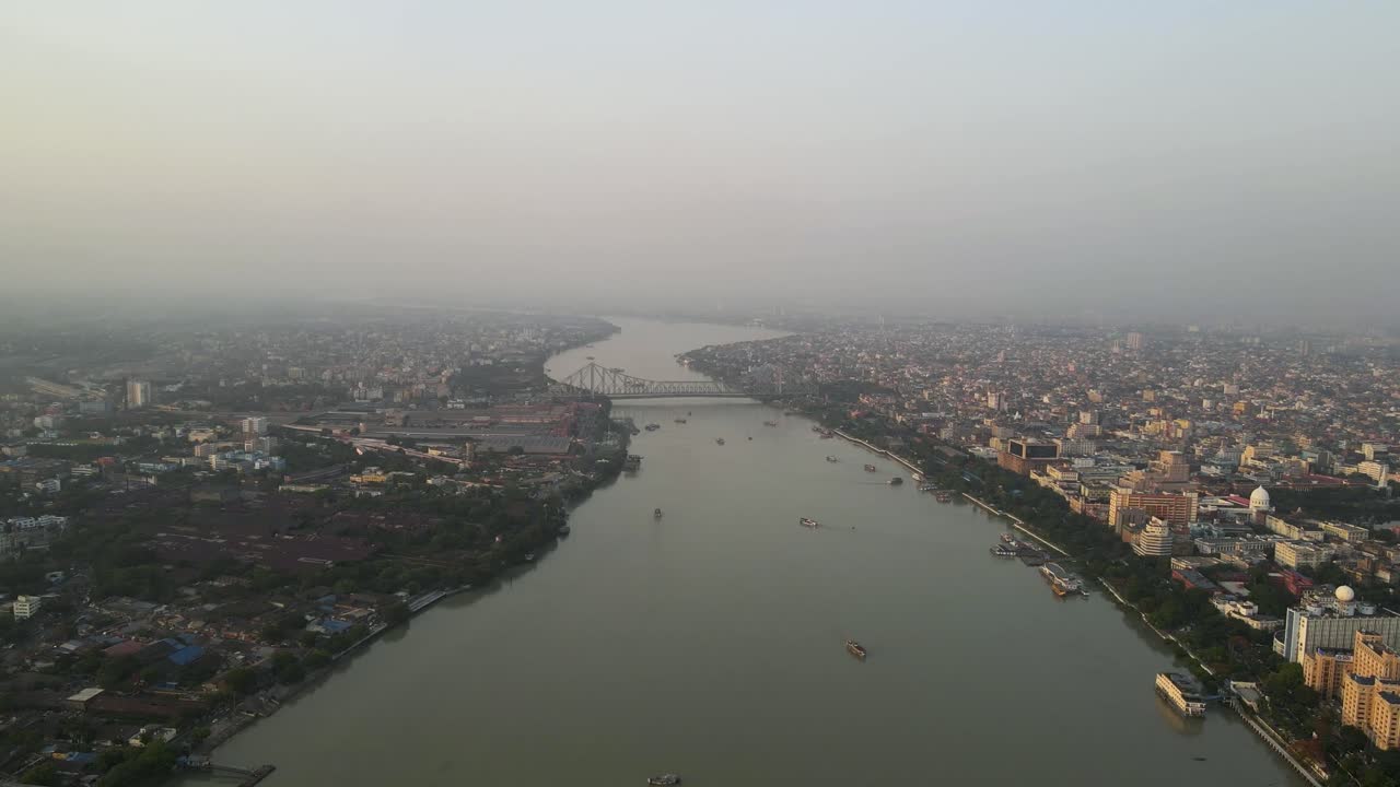 Stunning aerial view of the iconic Howrah Bridge over the serene waters of the Hooghly River in Kolkata.