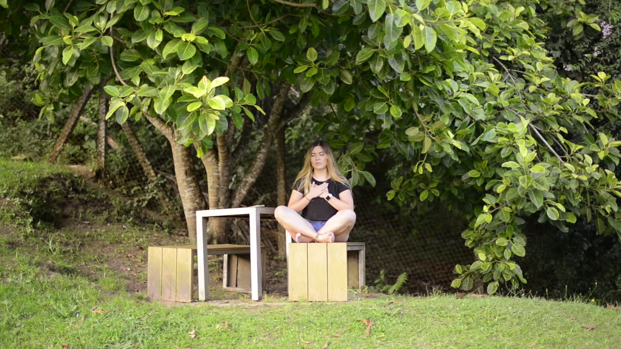 прекрасная блондинка медитирует в позе лотоса в природе.