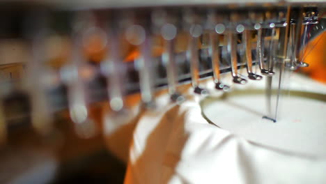 closeup view of an automated embroidery machine working on a textile design, stitching a pattern onto a shirt. focus on precision needlework, textile production, and garment customization