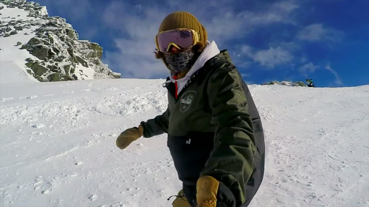 Ripresa d'azione al rallentatore di un uomo che scende agilmente su una pista da sci con lo snowboard.