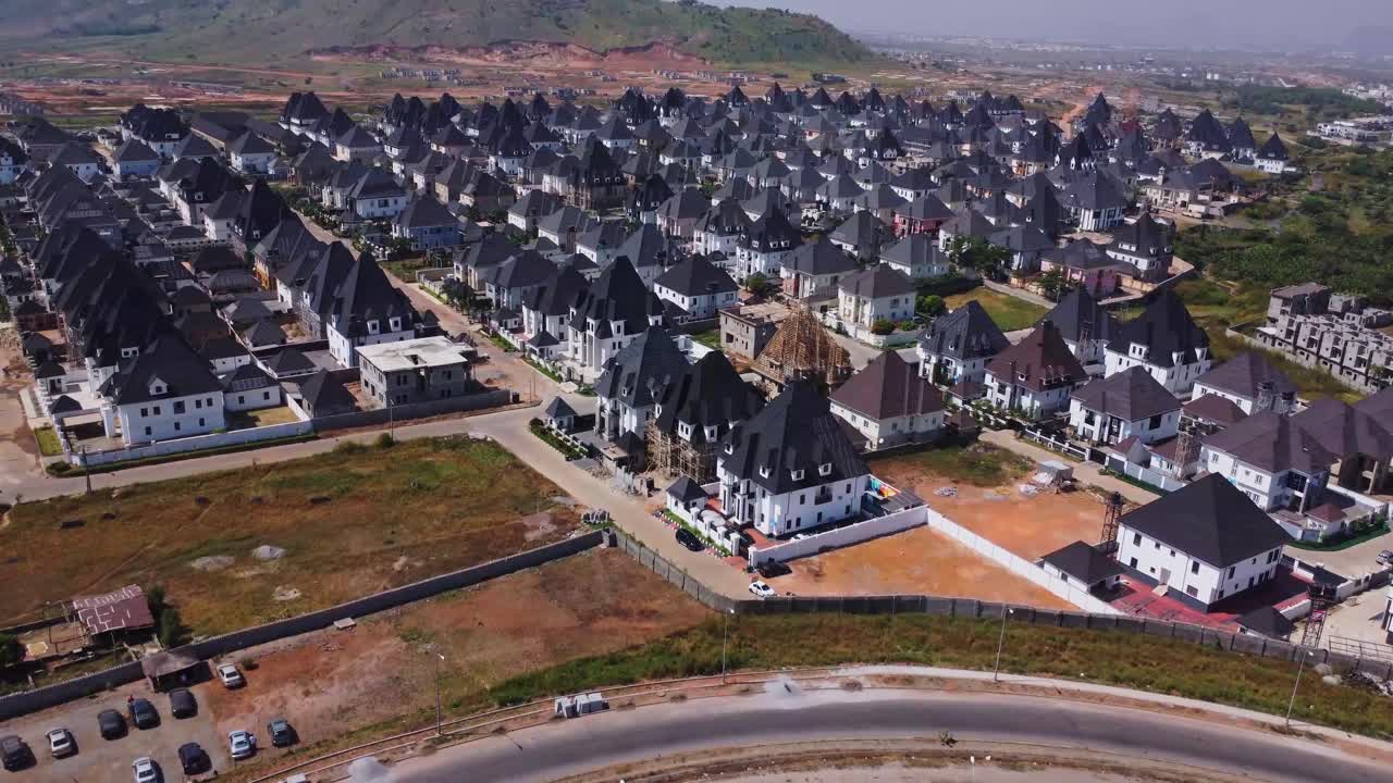 Beautiful aerial of a peaceful and wealthy suburban neighborhood with large standalone houses near major express road in Abuja, Nigeria on a sunny day