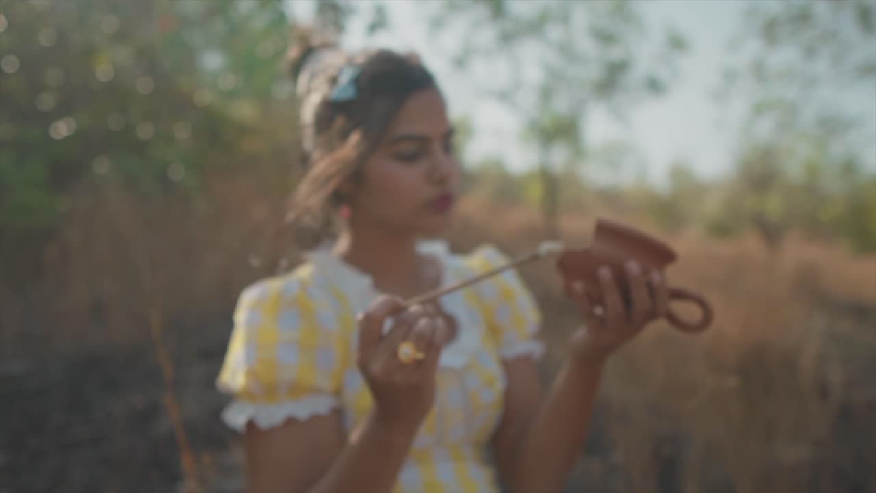 cámara lenta de ensueño alejarse de una joven hermosa mujer india pintando una vasija de barro rota en sus manos al aire libre