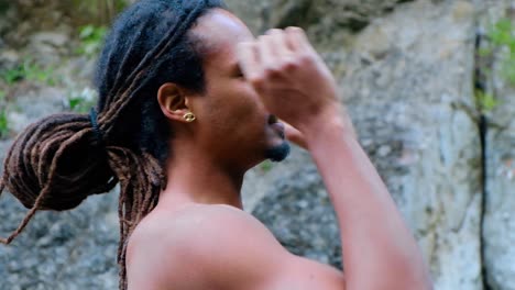 side view of mixed race man fixing his hair isolated on rocky background - closeup shot