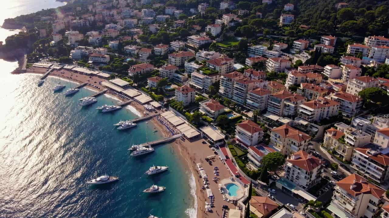 Video aereo di una cittadina costiera con tetti vivaci e yacht lungo la costa