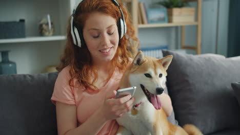 woman and shiba inu relaxing on a couch with headphones and phone