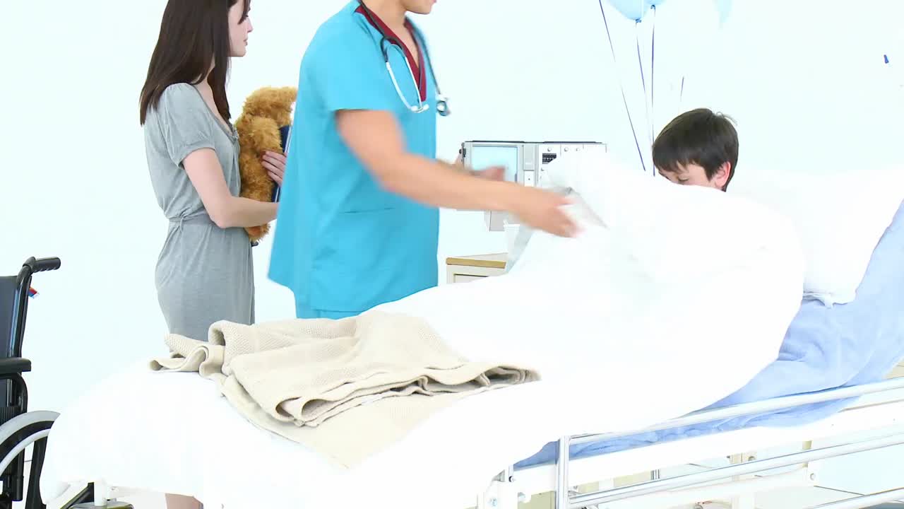 小さな男の子がベッドに入るのを手伝う医師