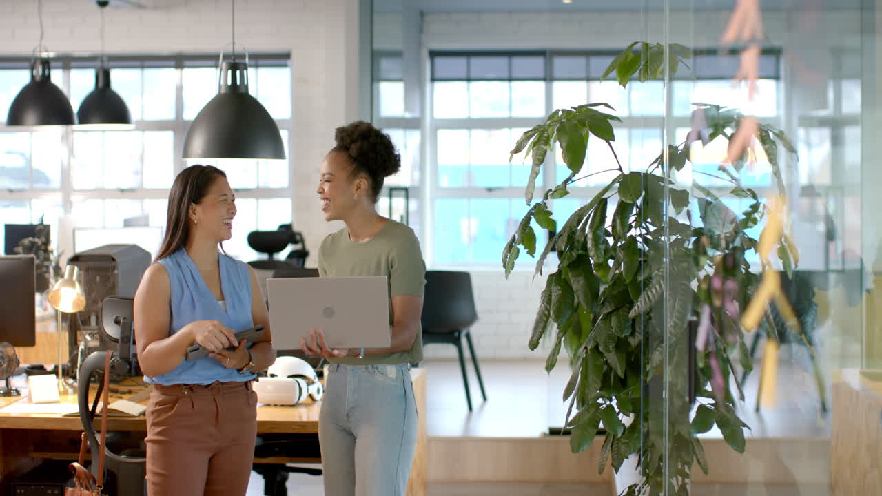Biracial and African American women discuss business work in a modern office