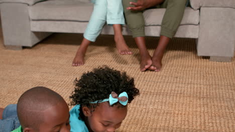 siblings using laptop on the floor while parents watch